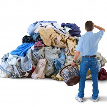man holding laundry basket piles of laundry washing machines
